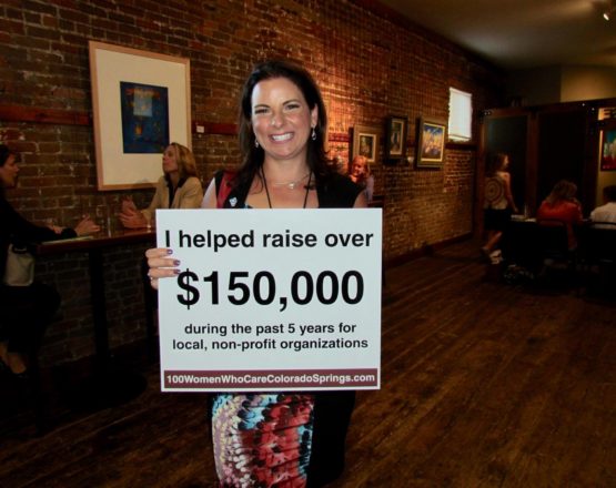 woman holding sign of amount raised for 100 women who care colorado springs
