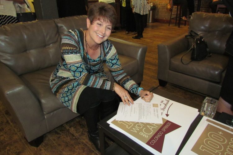 woman filling out committment form for 100 women who care colorado springs
